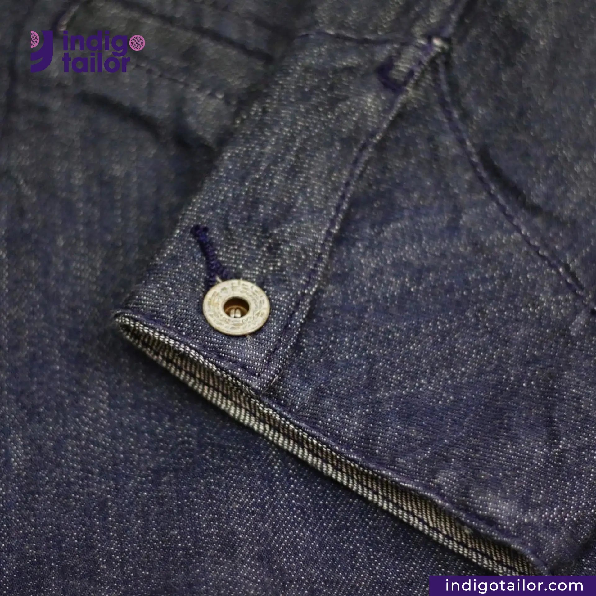 Close-up of a button on a FLIGHT JACKET with 'Indigotailor' branding.