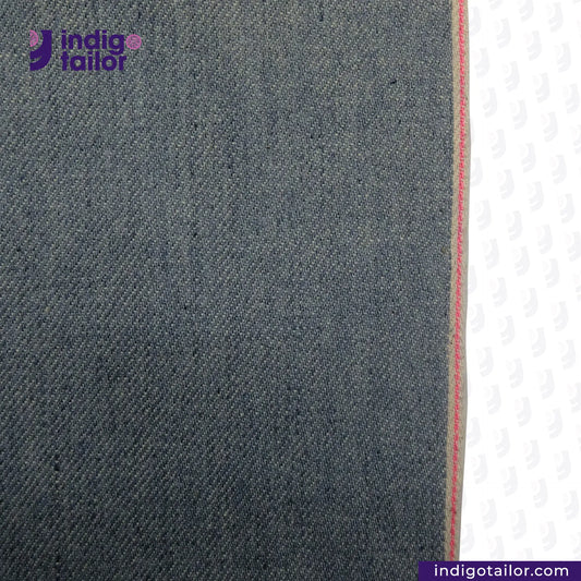Close-up of ICE BLUE SELVEDGE DENIM fabric with a visible brand logo and website.
