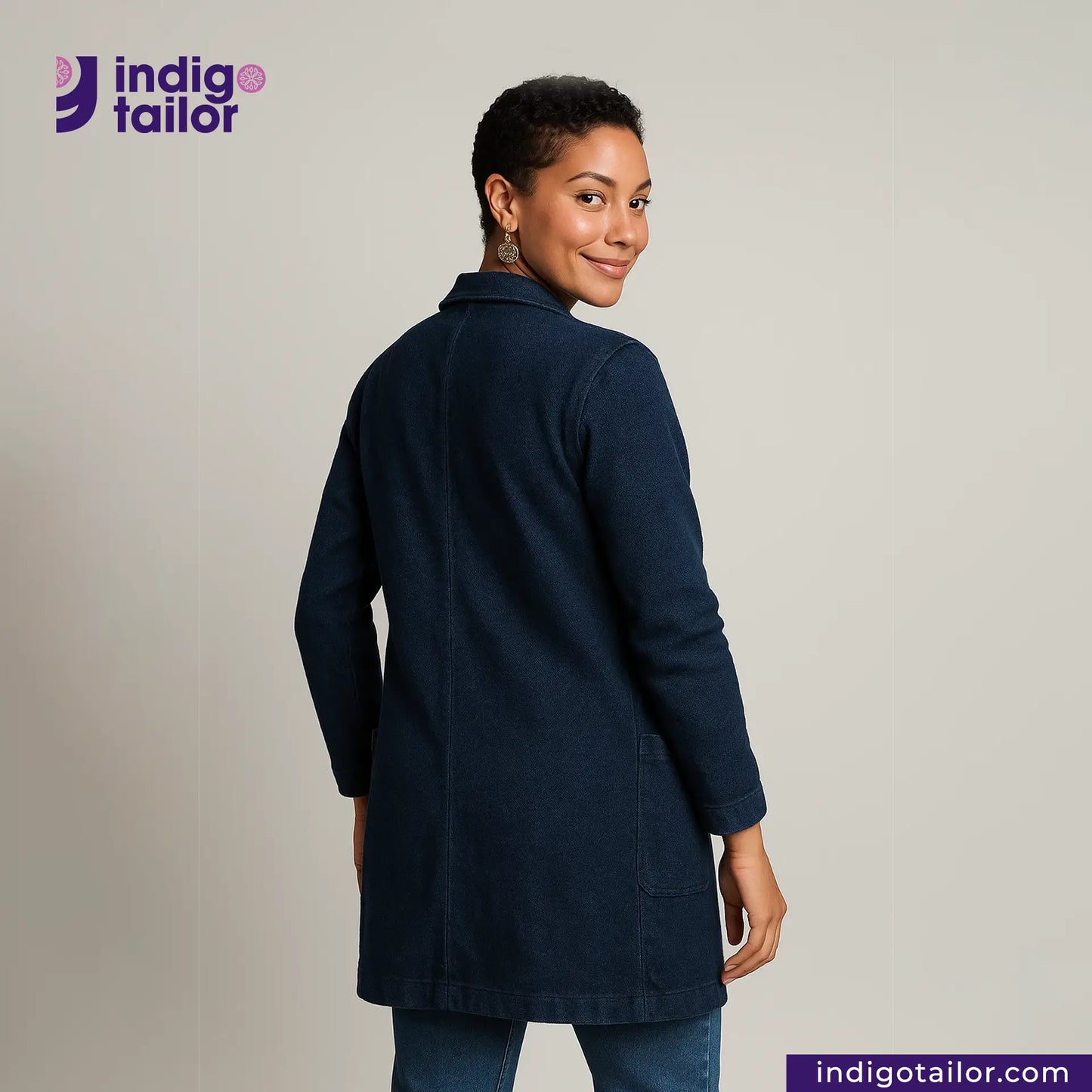 Woman wearing a INDIGO DYED LAB COAT with 'Indigo Tailor' logo and website on a gray background