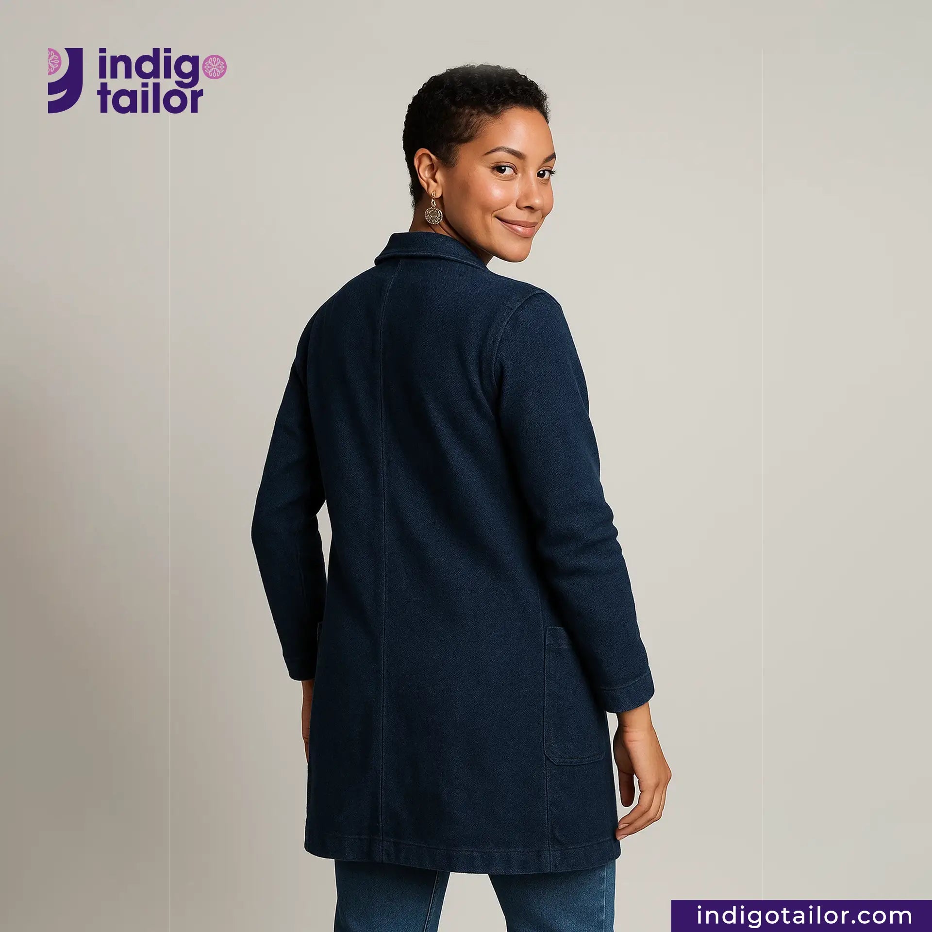 Woman wearing a INDIGO DYED LAB COAT with 'Indigo Tailor' logo and website on a gray background