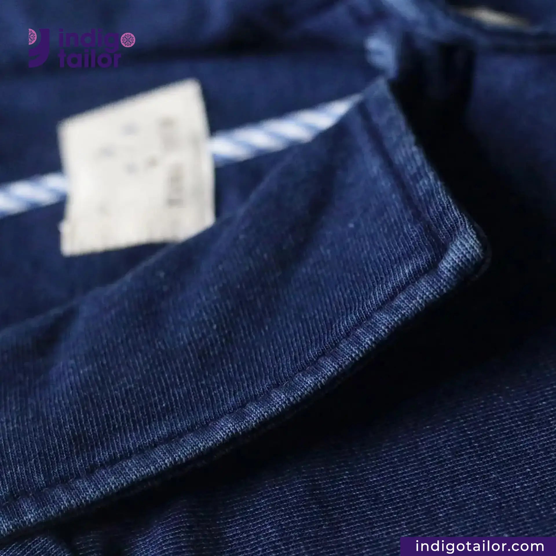 Close-up of INDIGO DYED LAB COAT fabric with a brand label, featuring 'Indigo Tailor' branding.