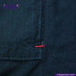 Close-up of INDIGO HARRINGTON JACKET with a brand logo and text.