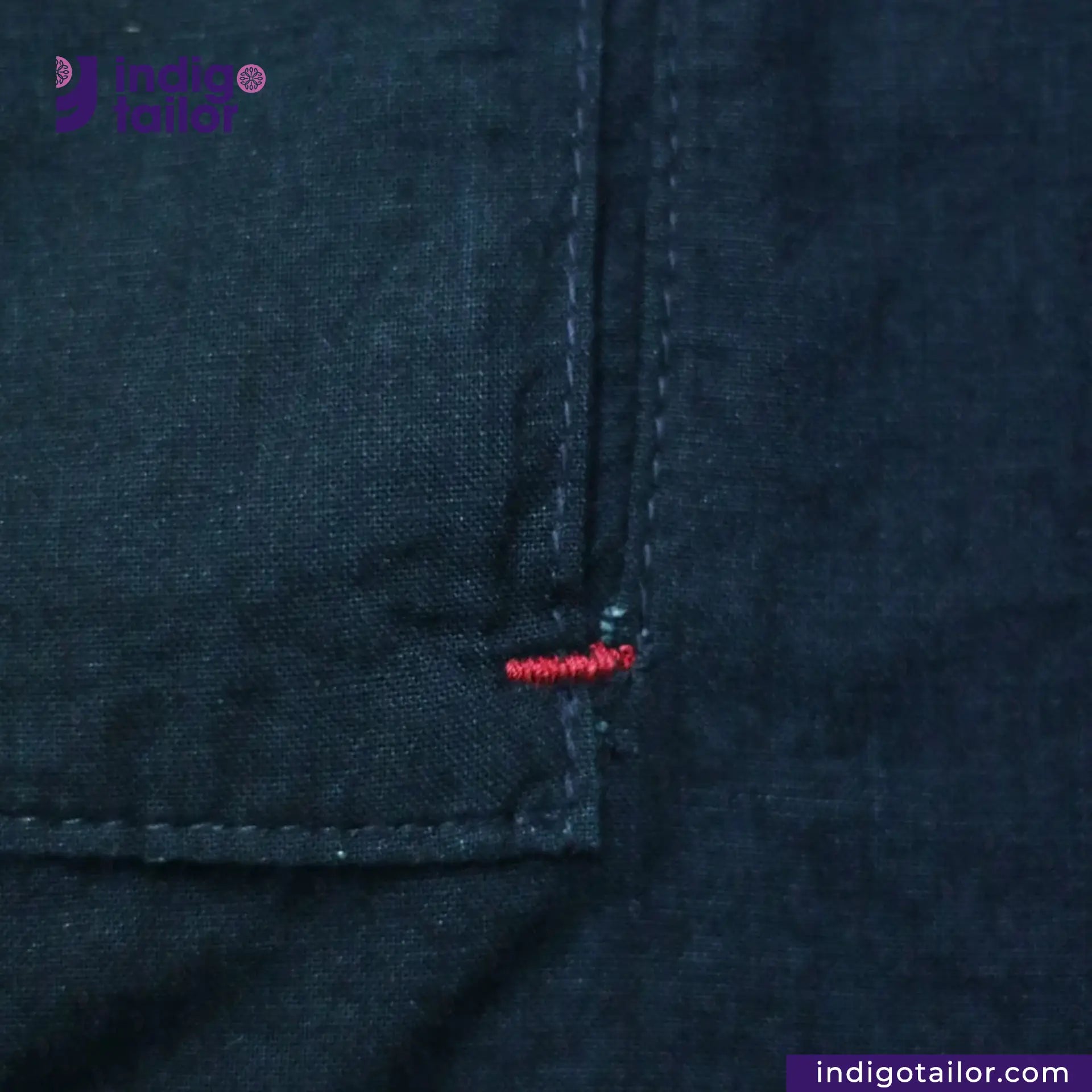Close-up of INDIGO HARRINGTON JACKET with a brand logo and text.
