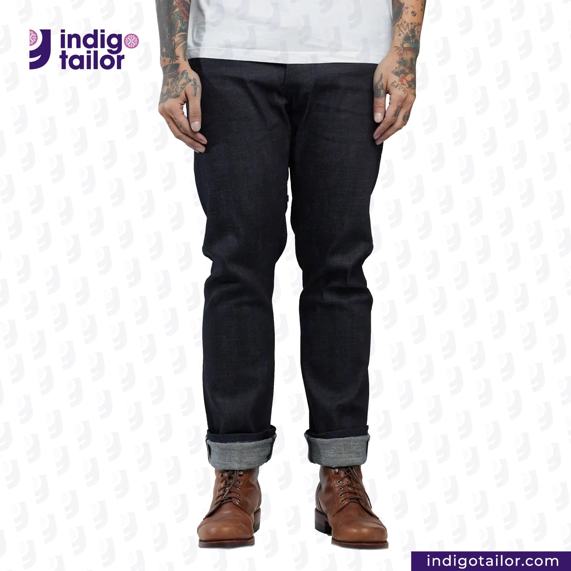 Person wearing INDIGO SAKURA DENIM jeans with rolled-up cuffs and brown boots on a white background, with 'Indigo Tailor' branding.