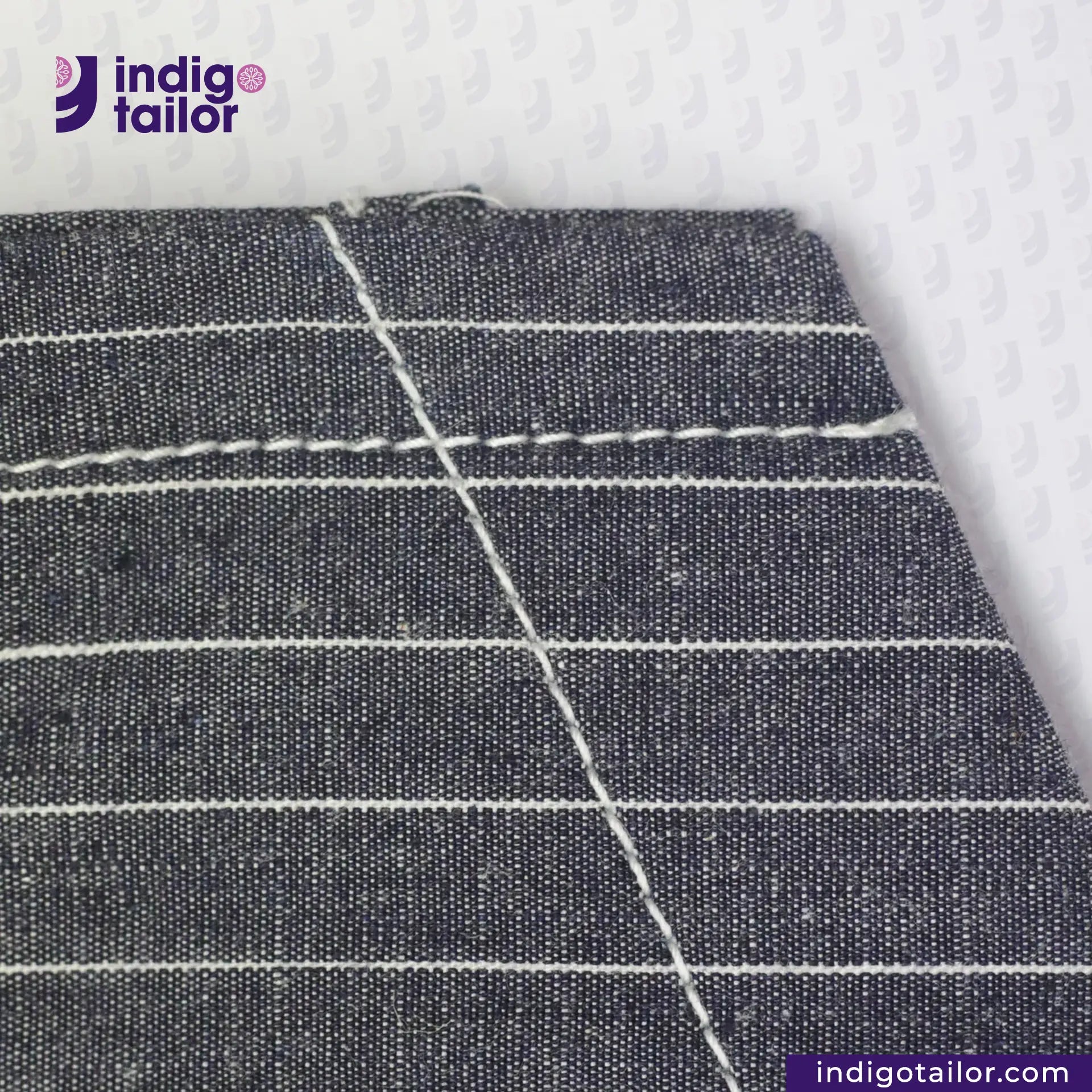 Close-up of INDIGO VINTAGE STRIPE WORK VEST with white stitching on a textured white background, featuring the Indigotailor logo.