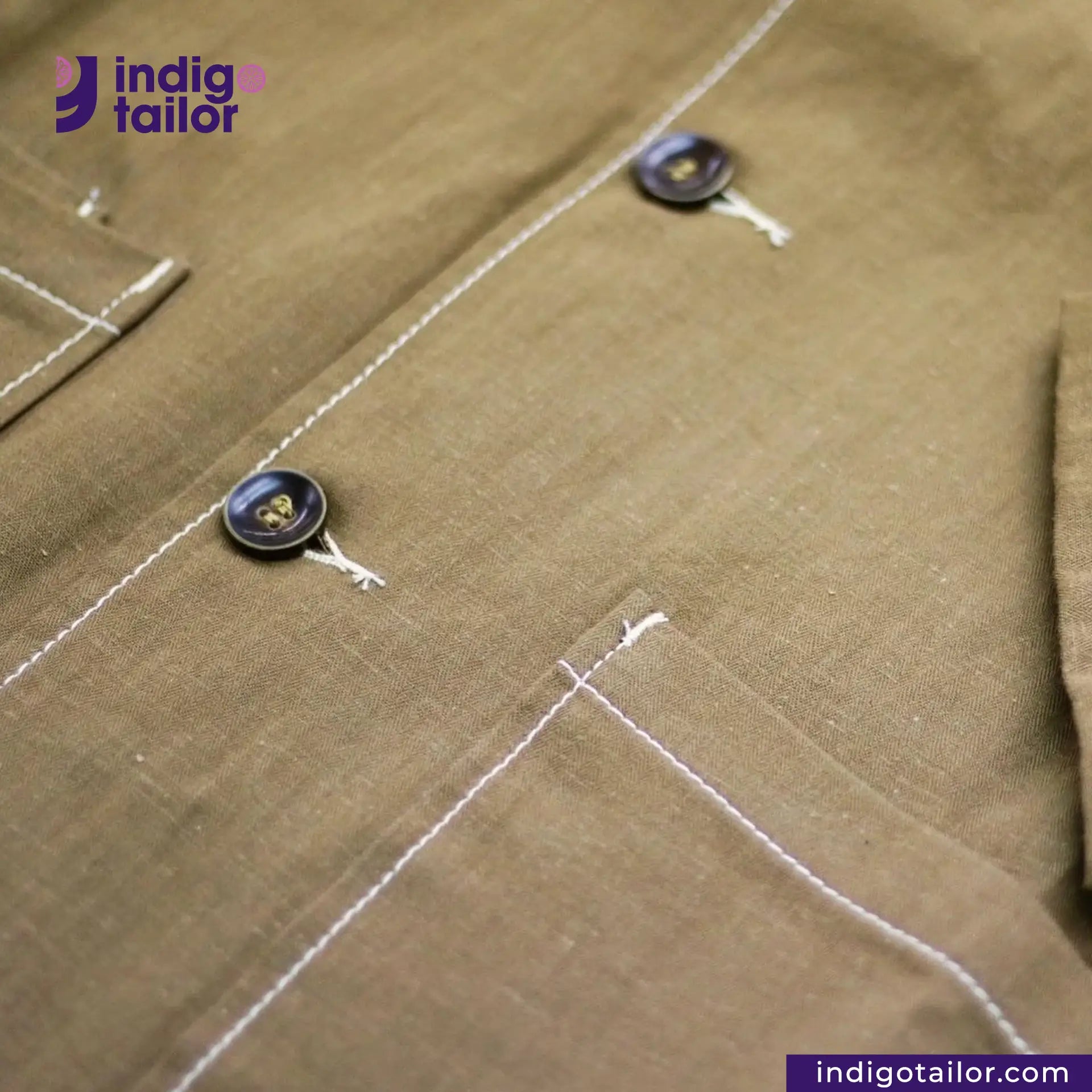 Close-up of a KHAKI HERRINGBONE COVERALL JACKET with buttons and stitching, featuring the Indig Tailor logo.