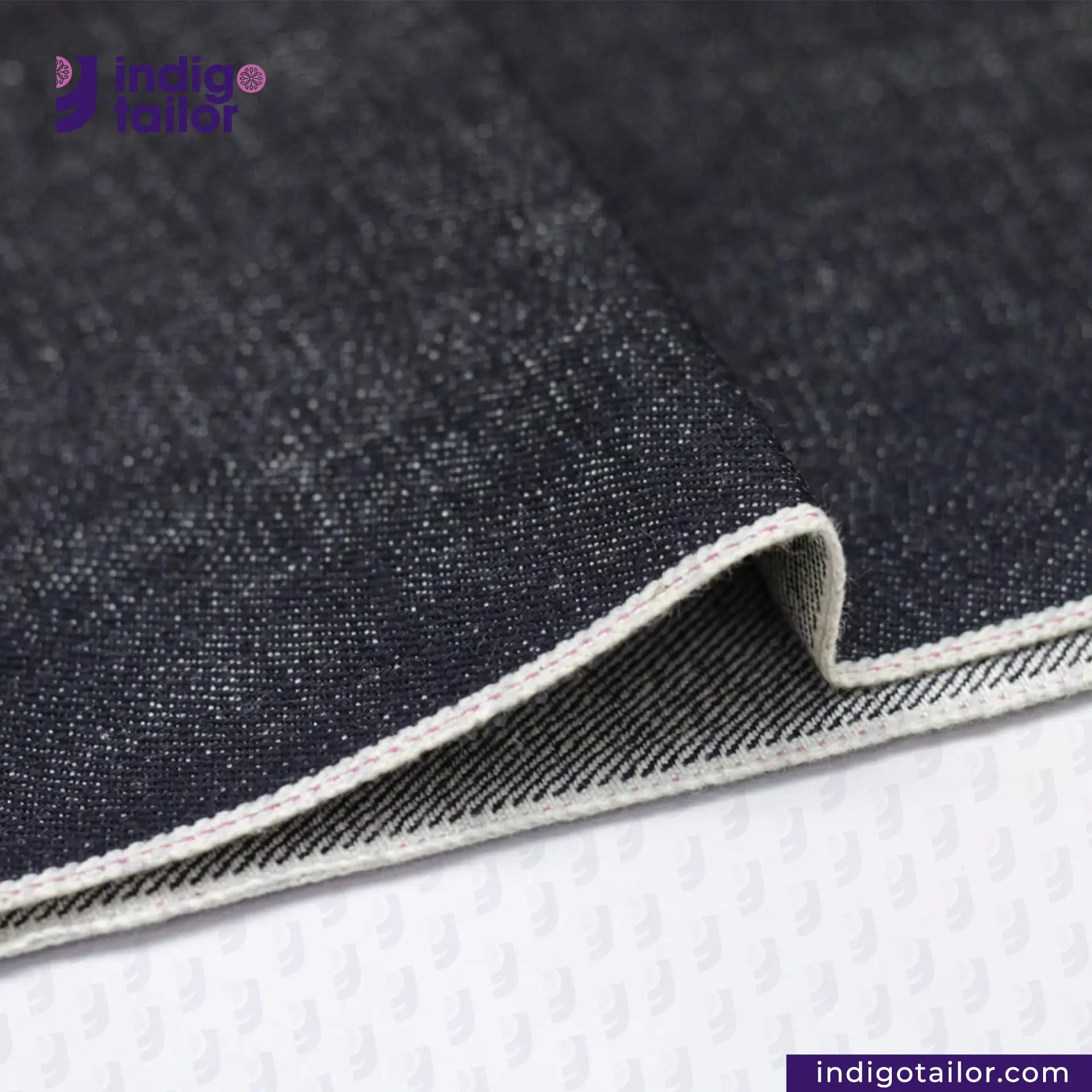 Close-up of KUROKI SLUBBY AND HEAVY DEEP INDIGO PINK SELVEDGE fabric with a visible brand logo, on a white background.