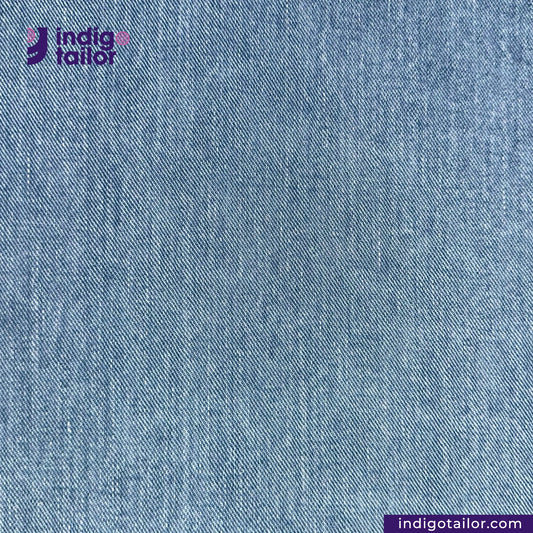 Close-up of LIGHT WASHED SELVEDGE DENIM LIME SELVEDGE fabric with 'Indigotailor' logo in the corner.