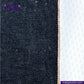 Close-up of LOW TENSION SLUBBY, NEPPY AND HEAVY SELVEDGE DENIM fabric with a white background, featuring the Indigo Tailor logo.