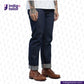 Person wearing MEDIUM BLUE DENIM LIVIDUS SELVEDGE jeans and brown shoes on a white background with 'Indigo Tailor' branding.