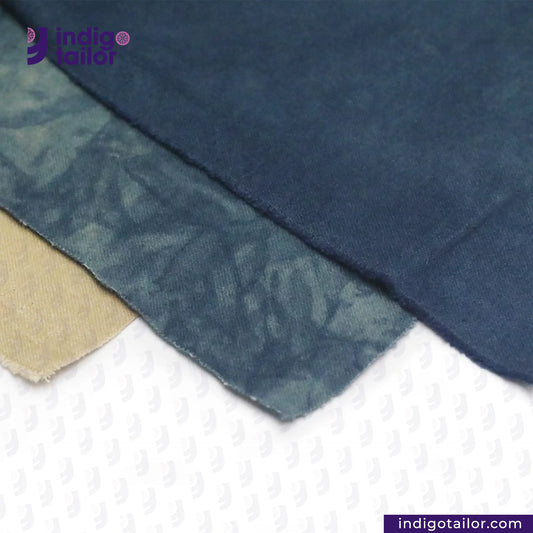 Close-up of NATURAL INDIGO DYED SUEDE fabric with a textured pattern on a white background, featuring the 'Indigotailor' brand.