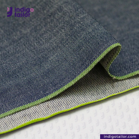 Close-up of OCEAN BLUE COTTON HEMP BLEND SELVEDGE DENIM fabric with green edge, featuring Indigotailor logo.