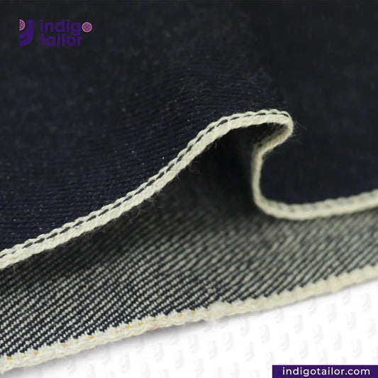 Close-up of OMOTAI GREENCAST SELVEDGE DENIM fabric with visible stitching, branded 'Indigotailor'.