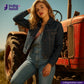 Woman in ORGANIC NATURAL COTTON SELVEDGE DENIM outfit posing in front of a red tractor with 'Indigotailor' branding.