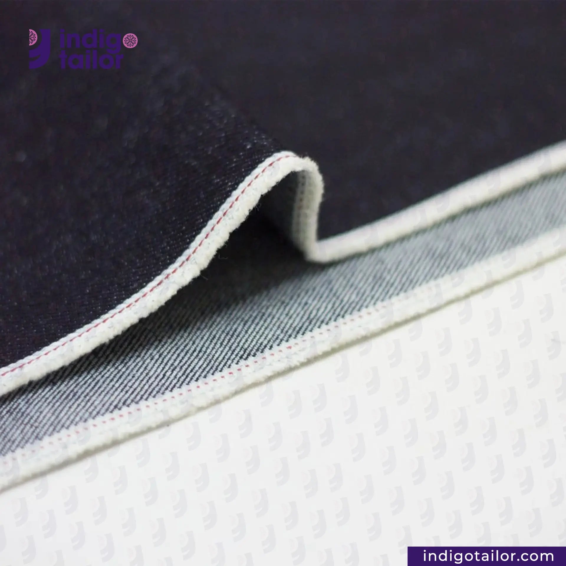Close-up of ORIGINAL BLUE SELVEDGE DENIM fabric with visible stitching, featuring the Indigotailor logo.