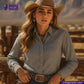 Woman wearing a cowboy hat and REVERSIBLE CHAMBRAY BLUE GREY WITH SUBTLE HICKORY STRIPES shirt leaning against a wooden fence with 'Indigotailor' branding.