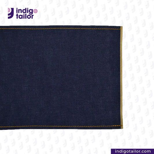 SATURATED INDIGO GOLDEN SELVEDGE fabric with yellow stitching on a white background, featuring the Indigo Tailor logo.