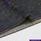 Close-up of TATE OCHI DOUBLE RING SPUN SELVEDGE DENIM fabric with red stitching on a white background, featuring the Indigo Tailor logo.