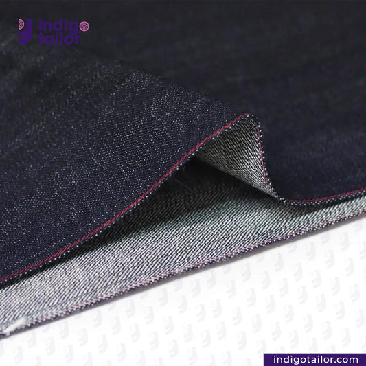 Close-up of TROPIC CITY DENIM fabric with visible stitching, featuring the Indigo Tailor logo.