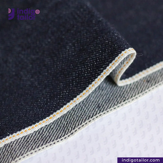 Close-up of TWO TONE SELVEDGE PAPER WEIGHT DENIM fabric with visible stitching, featuring the Indigotailor logo.