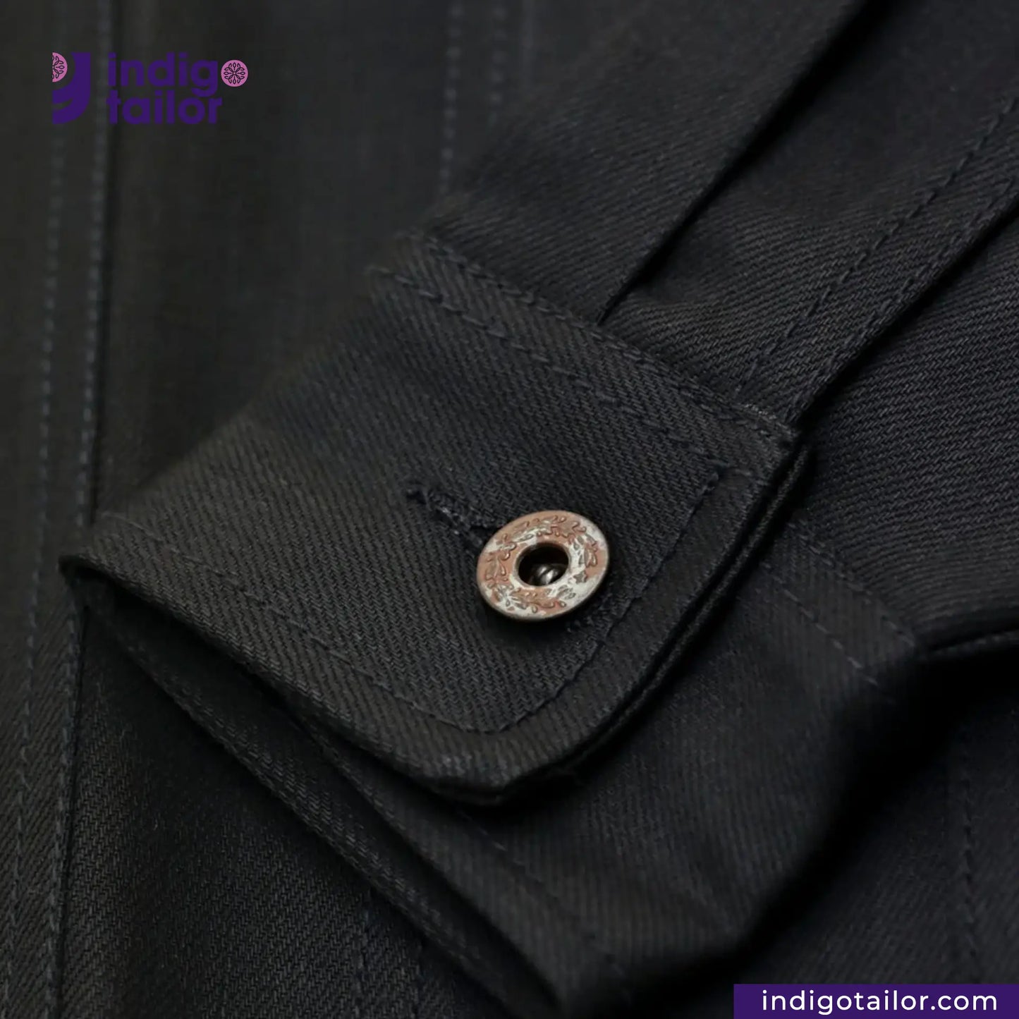 Close-up of a TYPE III DOUBLE BLACK TRUCKER JACKET with a button, featuring the brand 'Indigotailor'.