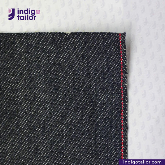 Close-up of UNSANFORIZED LOOM-STATE KIBATA DENIM fabric with a red stitch on a white background, featuring the Indigotailor logo.
