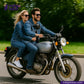 Two people riding a motorcycle on a road with greenery in the background, featuring the brand 'Indigotailor'. wearing VINTAGE SLUB DENIM outfits
