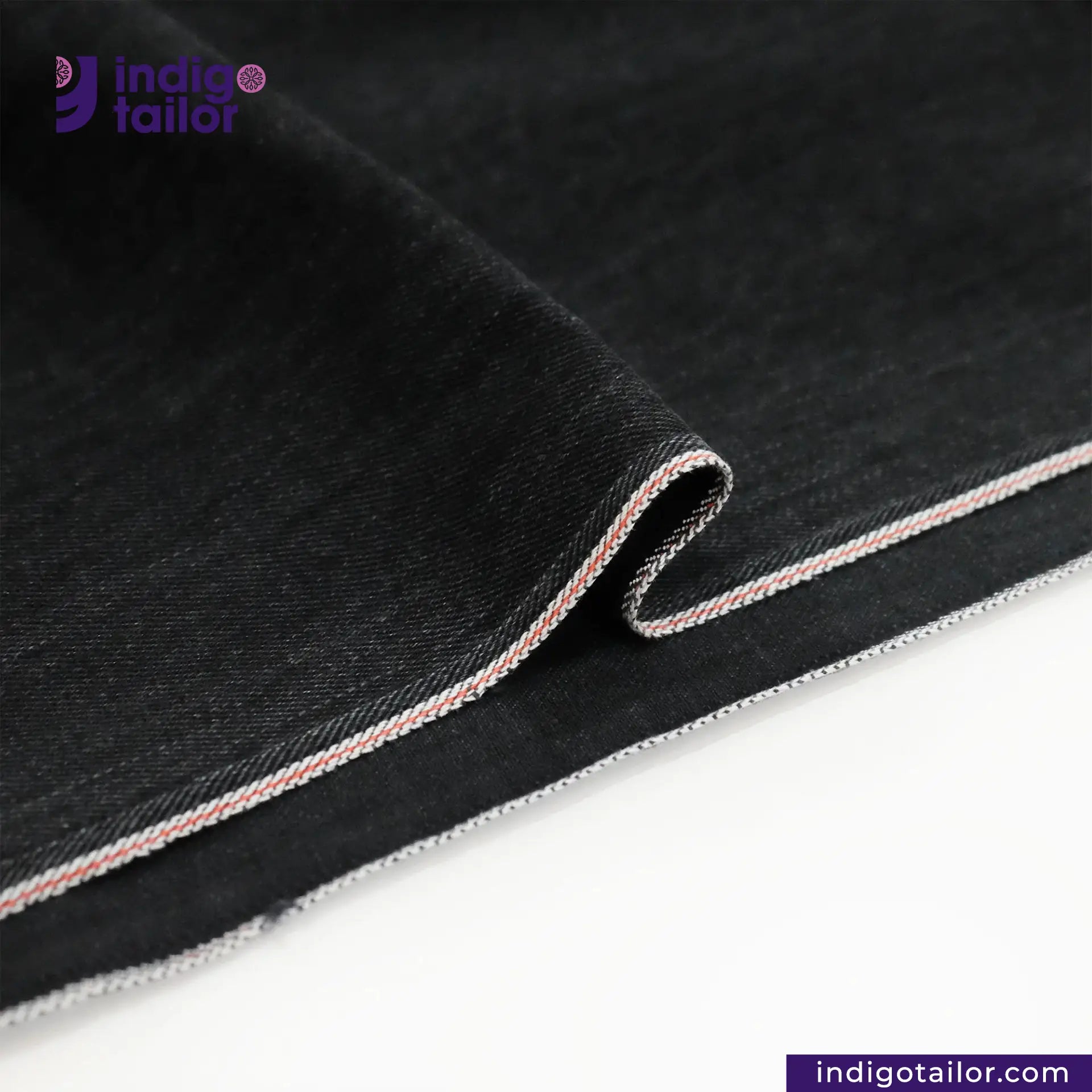 Close-up of WASHED BLACK x BLACK SELVEDGE DENIM fabric with a visible brand logo on a white background